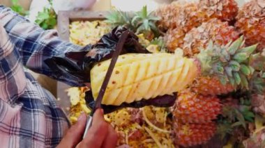 Sokak satıcıları renkli bir meyve tezgahında ananas soyarken ve keserken usta bir şekilde sokakta, Asya 'da, Hindistan' da meyve satan bir adam.
