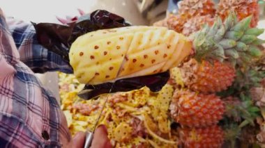 Sokak satıcıları renkli bir meyve tezgahında ananas soyarken ve keserken usta bir şekilde sokakta, Asya 'da, Hindistan' da meyve satan bir adam.