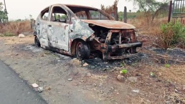Yol kenarında yanmış ve terk edilmiş bir araba enkazı var. Yol kenarında, Asya 'da, Hindistan' da park halindeki bir otoyolda kaza üstüne yangın ve yangın sonucu oluşan hasar görülüyor.
