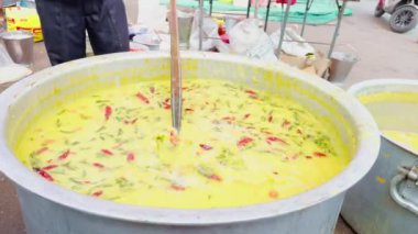 Bir adam açık havada büyük bir tencerede yemek pişiriyor ahşap kaşık, canlı renkler, büyük etkinlik veya geleneksel evlilik için açık hava yemekleri, Asya ve Hindistan ile karıştırılıyor.