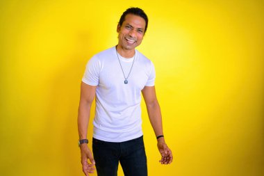 Stüdyoda çılgınca gülüyordu, beyaz tişörtlü adam sarı arka plana gülüyordu. Mutluluğu ifade etmek. Dişli gülümseme. Diş bakımı. Hintli. Kahkaha diş konsepti. Adam başarıyı seviyor, Asyalı, 30 'larında.