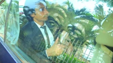 Şarap kadehiyle arabada oturan bir işadamı arka koltukta oturan bir adam, dışarıdan bakan bir adam.