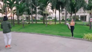 Parkta yoga minderiyle duran bir kadın spor sutyenli genç bir kadın antrenmana hazırlanıyor, Hintli.