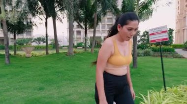 Spor sutyeniyle koşan bir kadın, patikada koşan genç bir kız, bina bahçesi, kadın koşucu, sabah egzersizi, Hindistan, günlük rutin çalışma.