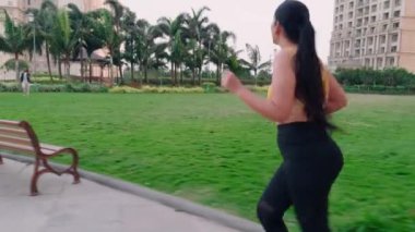 Spor sutyeniyle koşan bir kadın, patikada koşan genç bir kız, bina bahçesi, kadın koşucu, sabah egzersizi, Hindistan, günlük rutin çalışma.