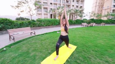Yoga yapan Hintli kadın, savaşçı pozu veren genç bayan, şehir merkezinde günlük egzersiz yapan kadın.