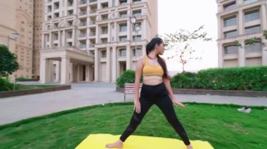 Yoga yapan Hintli kadın, savaşçı pozu veren genç bayan, şehir merkezinde günlük egzersiz yapan kadın.