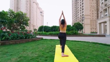 Yoga yapan Hintli kadın, savaşçı pozu veren genç bayan, şehir merkezinde günlük egzersiz yapan kadın.