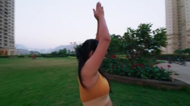 Yoga yapan Hintli kadın, savaşçı pozu veren genç bayan, şehir merkezinde günlük egzersiz yapan kadın.