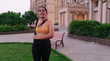 Spor kıyafetleriyle yürüyen genç bir bayan, inşaat yolunda yürüyen bir kadın, yoga minderi taşıyan güzel bir kadın, Hintli.