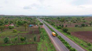 Otoyol üzerinde insansız hava aracı vuruldu, otobanın havadan görünüşü yemyeşil arazide, arka planda tepeler olan bir yerden geçiyor, yol yeşil ve kahverengi toprak parçalarıyla çevrili, Hindistan.