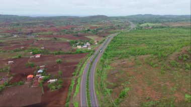Otoyol üzerinde insansız hava aracı vuruldu, otobanın havadan görünüşü yemyeşil arazide, arka planda tepeler olan bir yerden geçiyor, yol yeşil ve kahverengi toprak parçalarıyla çevrili, Hindistan.