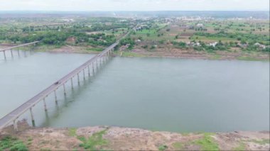 Birden fazla köprüsü olan bir nehrin havadan görünüşü, oradan geçen kamyonlar, yeşillik ve küçük bir kasaba, çekimin üstündeki Ganga kanalı, Hindistan