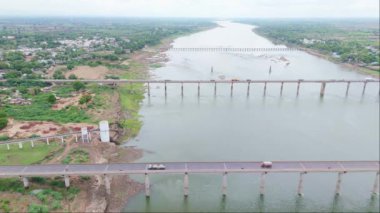Birden fazla köprüsü olan bir nehrin havadan görünüşü, oradan geçen kamyonlar, yeşillik ve küçük bir kasaba, çekimin üstündeki Ganga kanalı, Hindistan