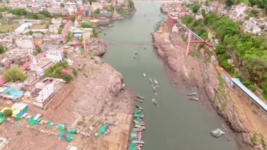Nehir üzerindeki binaları birleştiren köprülerin hava görüntüsü yeşil alanlarla çevrili insansız hava aracı görüntüleri derenin yanındaki köy, tekneler yanaştı, Hindistan. 