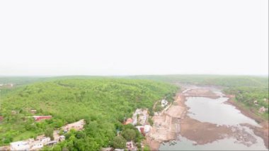 Nehir üzerindeki binaları birleştiren köprülerin hava görüntüsü yeşil alanlarla çevrili insansız hava aracı görüntüleri derenin yanındaki köy, tekneler yanaştı, Hindistan. 