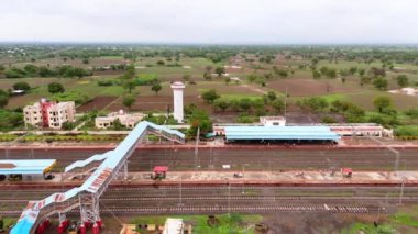 Demiryolu istasyonunun birden fazla raylı havadan görüntüsü, kırsal bölgedeki insansız hava aracı atış platformu, yeşil binalarla çevrili, yukarıdan boş demiryolu, Hindistan
