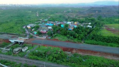 Gün batımında kırsal alan manzarası, yolu, demiryolu rayları, yeşil alanlar ve uzak bir yerdeki dağınık evler, Navi Mumbai Hindistan Maharashtra 'nın küçük köyü.