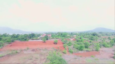 Doğa tarafından çevrelenmiş modern bir Villa 'nın havadan görünüşü, kırsal alanda güzel bir bungalov, Kızıl Topraklı tarım arazisi, yeşil ağaçlar, ekilmiş tarlalar, köy alanı, Hindistan kırsal kesimini gösteriyor.