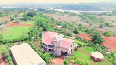 Yukarıdan gökyüzü manzarası, yükseklikten güzel dağ evi, bir köy, kırsal arazi karışımı evler, yeşillik ve kırmızı toprak, yüzme havuzlu büyük ev, Hindistan