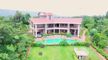 Yeşil bir arazide Modern Ev 'in Havadan Bakışı, Kırsal Alandaki Büyük Bungalov, yemyeşil yeşillik ve tarım arazileriyle çevrili, Chalet' in kırmızı çatısı ve geniş bahçesi, Hindistan