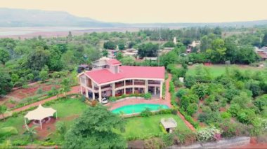 Yukarıdan gökyüzü manzarası, yükseklikten güzel dağ evi, bir köy, kırsal arazi karışımı evler, yeşillik ve kırmızı toprak, yüzme havuzlu büyük ev, Hindistan