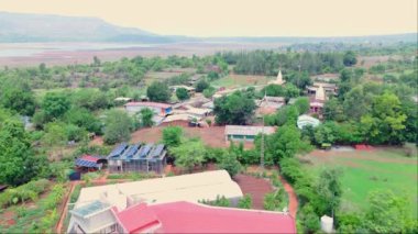 Yukarıdan gökyüzü manzarası, yükseklikten güzel dağ evi, bir köy, kırsal arazi karışımı evler, yeşillik ve kırmızı toprak, yüzme havuzlu büyük ev, Hindistan