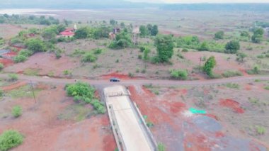 Köy Yolu 'nun havadan görünüşü, Kızıl toprak, seyrek bitki örtüsü ve dolambaçlı yol, insansız hava aracı, yeşillik, dağılmış ağaçlar ve çalılar, uzak bölgede, Hindistan, kırsal kesimde,