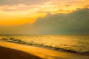 Denizde gün batımının doğal görüntüsü kıyıya doğru gelen küçük dalgalarla.
