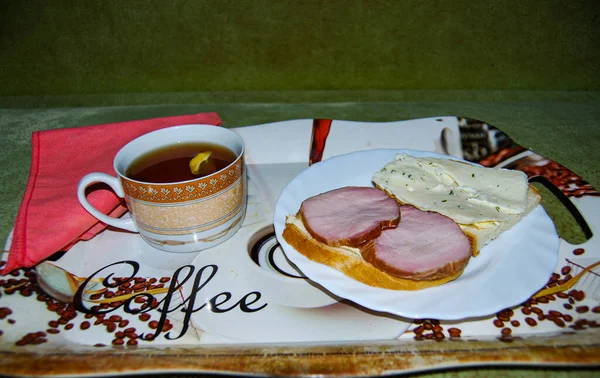 Tasty breakfast. Warm tea with sandwiches.Tea and two sandwiches with boiled pork and cheese.