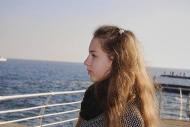 Denizin arka planında bir kız, uzaklığa bakıyor..