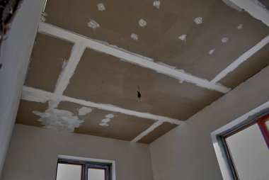 Alçıdan yapılmış pürüzsüz asılmış tavan. Özel bir evin tamiri, çürüme için tavanın hazırlanması..