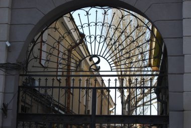 Çok güzel dövülmüş demir kapı, bir sürü bukleleri ve çubukları var. Kapıdan, ortasında bir ağaç büyüyen bir avlu görebilirsiniz..