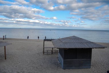 Odessa sahilinin manzarası. Odessanlar sonbahar plajında gezinip martıları besler. Sazdan çatılı bir kafe ve doğaçlama bir bar tezgahı boş..