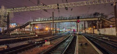 Odessa tren istasyonunun yollarına giriş. Uzaktan hareket eden bir tren görülebilir. Rayların üzerinde bir yaya geçidi var..