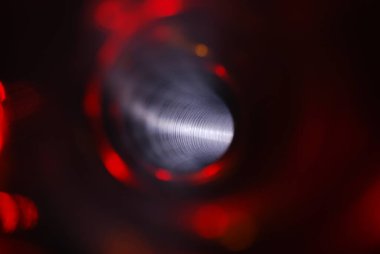 Parlak kırmızı kıvrımlı tünel. Borunun içinden bak. Boru hattının kıvrımlı, aydınlatılmış iç kısmı..