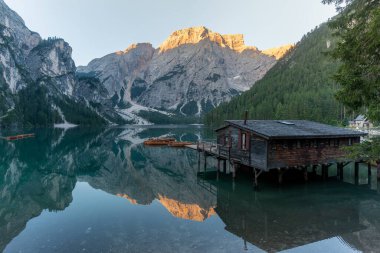 Dolomitlerdeki dağ zirvelerinin arka planında ahşap evleri olan göller.