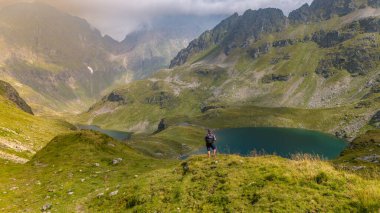 Genç adam gölün tepesinde yürüyüş yapıyor.