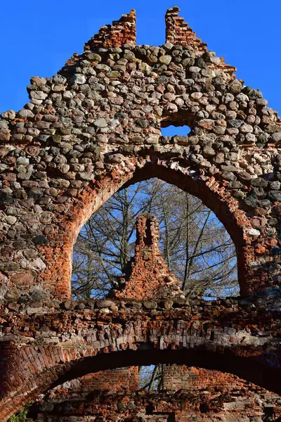 Ağaçları ve arka planında mavi gökyüzü olan eski bir kilisenin duvarlarından bir parça..