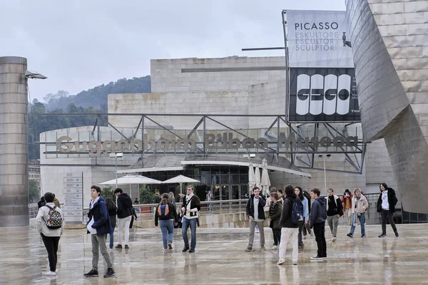 Bilbao, İspanya; 25 Kasım 2023: Guggenheim Müzesi girişinde çevresindeki meydandan ziyaretçilerin geçişini gözlemleyebiliriz. Posterlerinden birinde Picasso 'nun heykellerinin sergilendiğini de görüyoruz..
