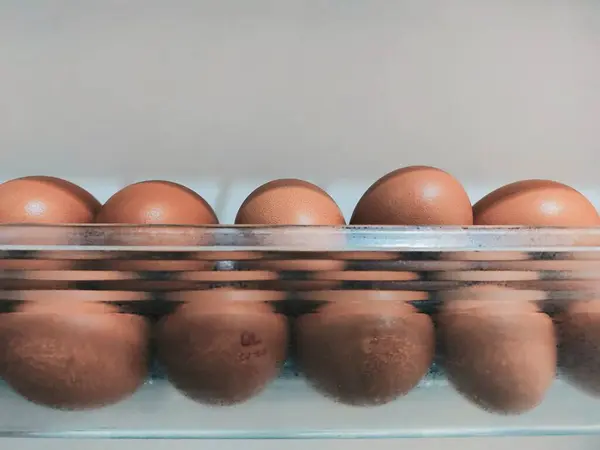 Şeffaf bir kabın içinde tavuk yumurtası yığını.