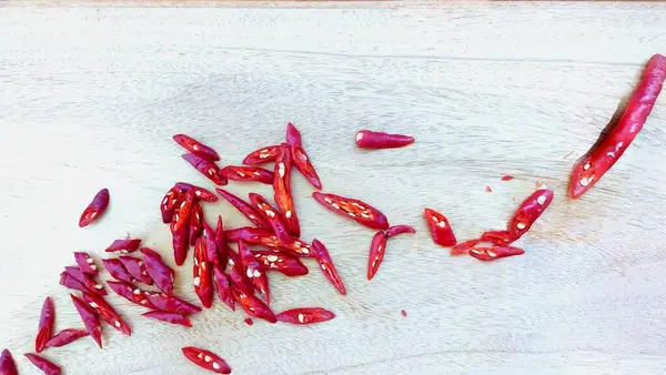 Ahşap kesme tahtasının üzerinde dilimlenmiş kırmızı biber.