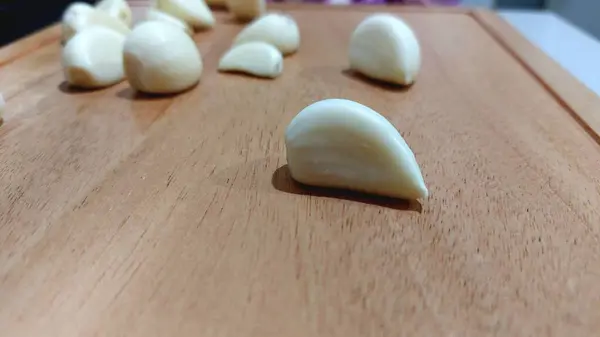 Kesme tahtasında soyulmuş bir grup sarımsak.