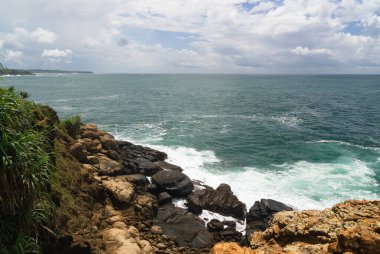 Fırtınalı gökyüzü ile kayalık tropikal kıyı şeridi
