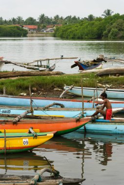 Nehirdeki birçok katamaran teknesinden birinde tek başına oturan balıkçı.