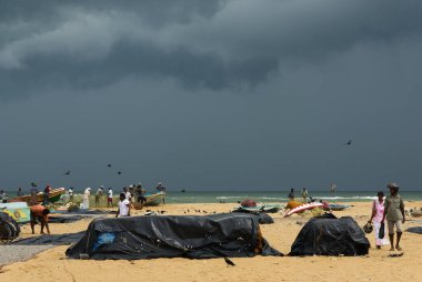 Balıkçılarla dolu bir sahilde şiddetli fırtına bulutları.