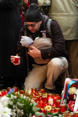 17 Kasım 1989 'da Narodni Trida' daki anma plaketinde bebeği olan bir baba mum yakıyor.
