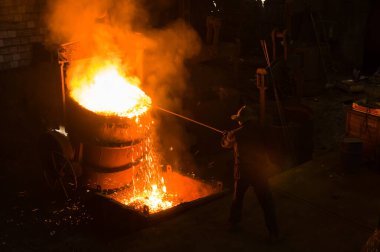 Metalürjist sıcak erimiş metalden gevşetir.