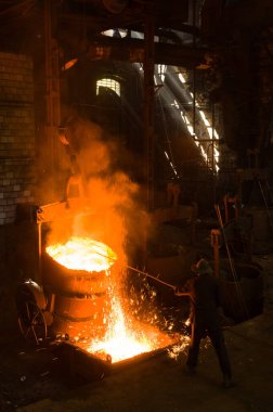 Metalürjist sıcak erimiş metalden gevşetir.