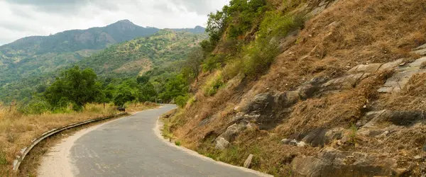 Bulutlu gökyüzü ile tepelik tropikal peyzaj boş dar yol